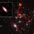 This composite image, taken by the Very Large Array and Hubble, shows the galaxy cluster MACS J0717.5+3745. Pullout shows the distant galaxy J0717+3745, far beyond the cluster, and likely the faintest radio-emitting object ever detected. The prominent red-orange objects are radio relics -- large structures possibly caused by shock waves -- inside MACS J0717.5+3745. Image credit: Heywood et al. / Sophia Dagnello, NRAO / AUI / NSF / STScI.